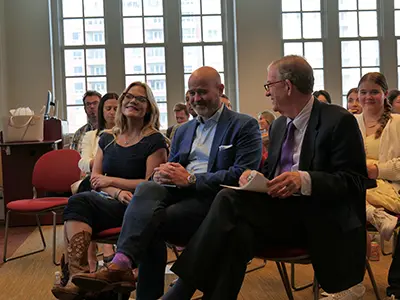 the dean and a speaker seated at Symposium